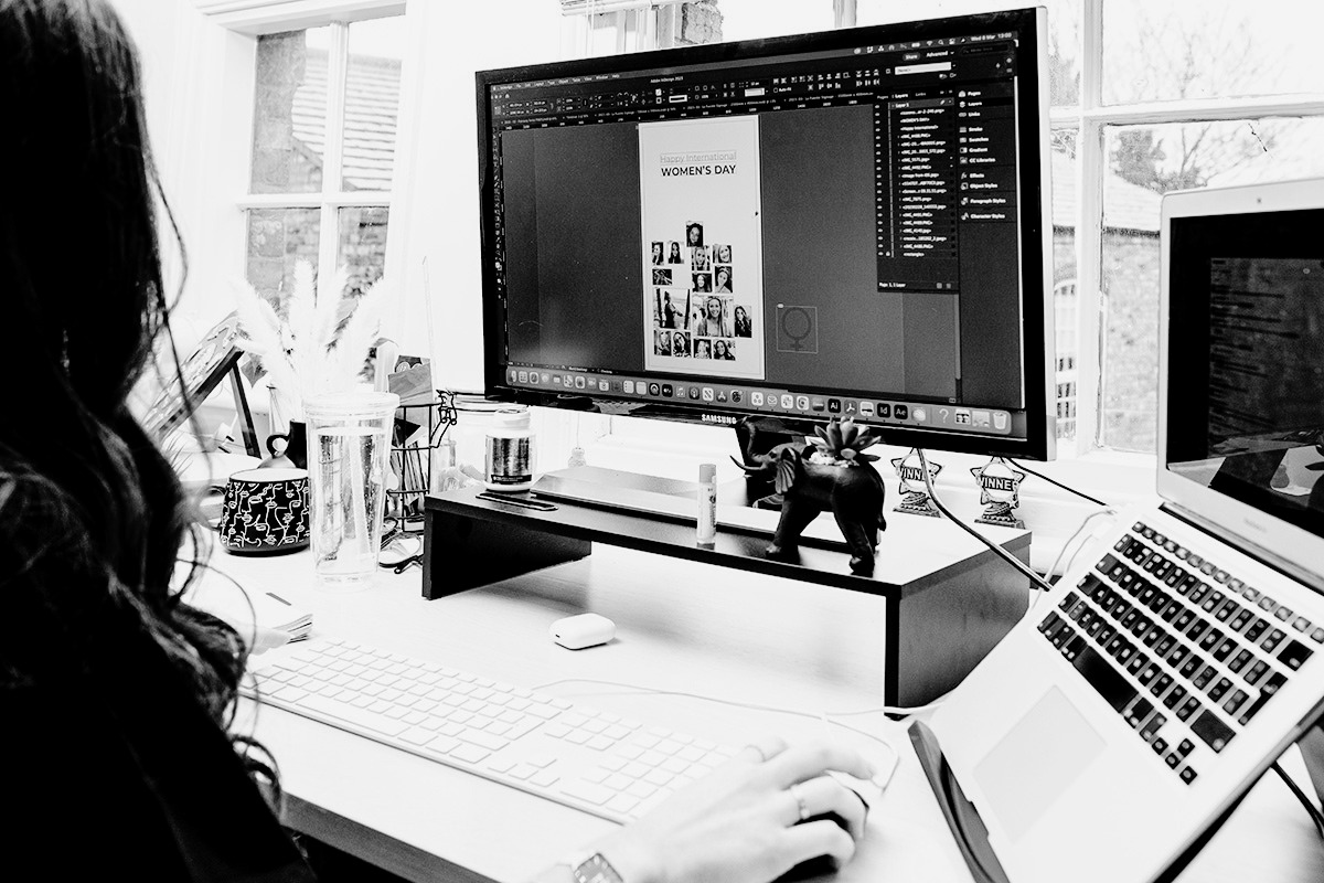 Person working on a social media graphic at a desktop computer in a bright studio workspace